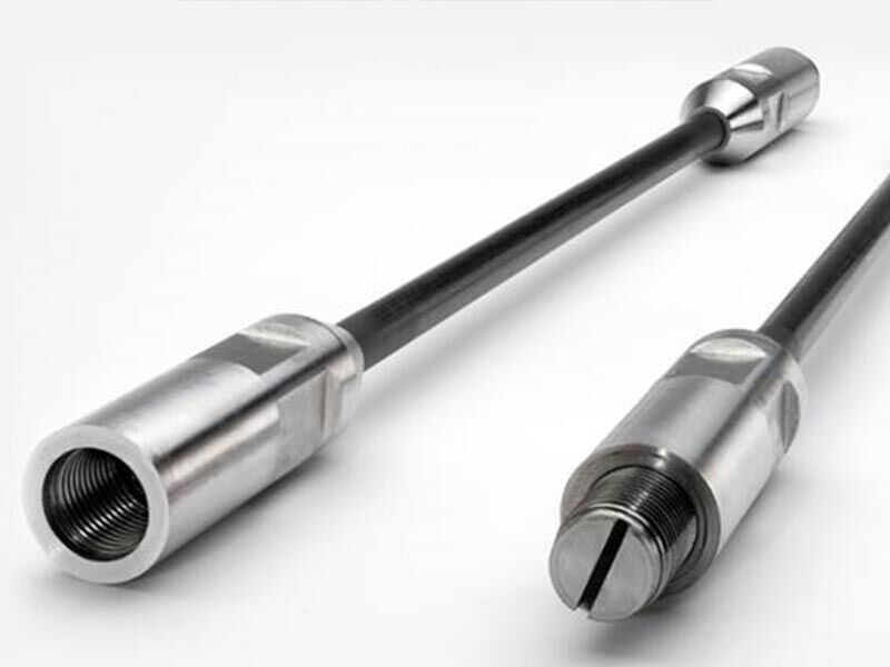 Two Megalex™ sucker rods laying on a white surface at an angle with its two alternate end-fixtures showing in the front of the image.